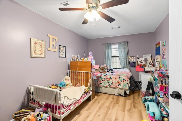 bedroom with wood finished floors, visible vents, and a ceiling fan