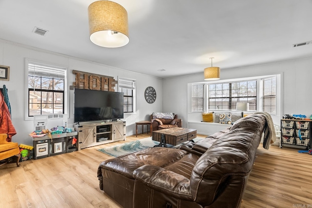 living room with wood finished floors, visible vents, and a healthy amount of sunlight