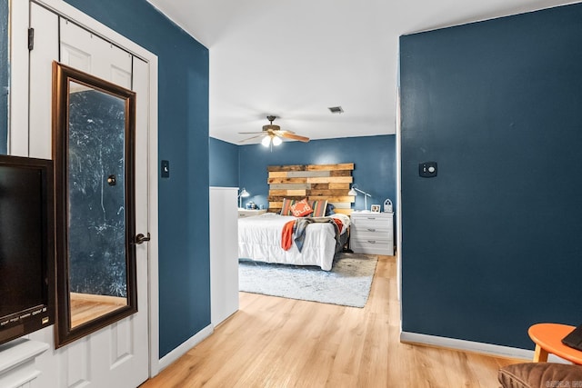 bedroom with ceiling fan, wood finished floors, visible vents, and baseboards