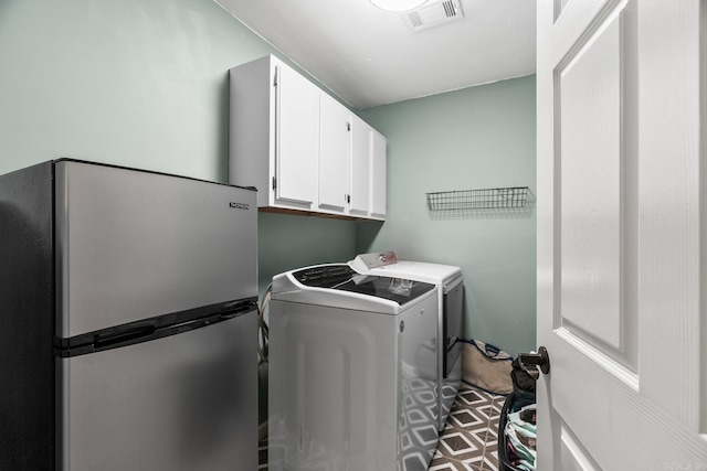 laundry area featuring independent washer and dryer, visible vents, and cabinet space