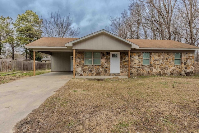 single story home featuring driveway, a carport, stone siding, and fence