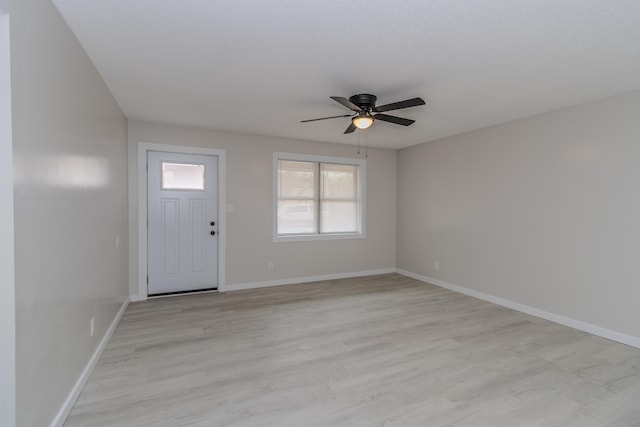 entryway with light wood-type flooring, a ceiling fan, and baseboards