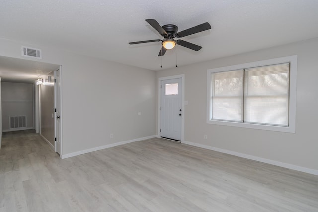 foyer entrance featuring light wood finished floors, visible vents, and baseboards