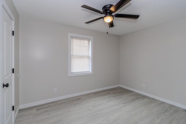 empty room with baseboards, ceiling fan, and light wood-style floors