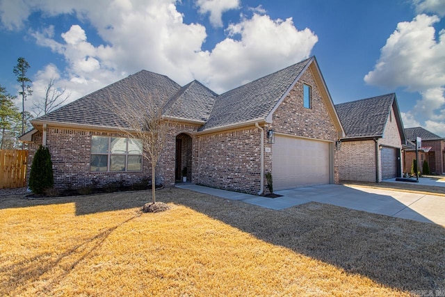 view of front of property featuring brick siding, a front yard, fence, a garage, and driveway