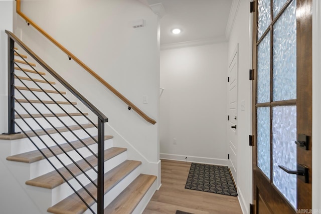 foyer entrance featuring baseboards, ornamental molding, wood finished floors, stairs, and recessed lighting