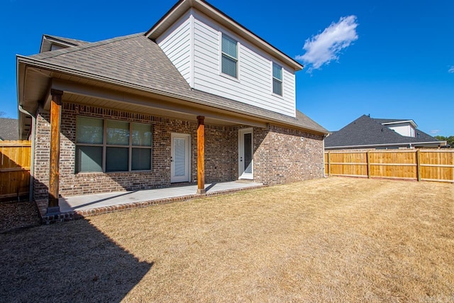 rear view of house with a fenced backyard, a patio, and brick siding