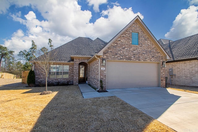 view of front of property with brick siding, roof with shingles, an attached garage, a front yard, and driveway