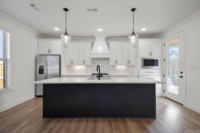 kitchen with stainless steel fridge, visible vents, an island with sink, built in microwave, and a sink