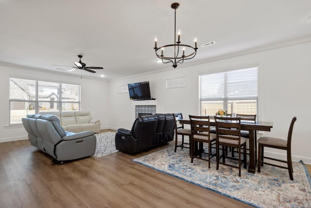 living area featuring a fireplace, wood finished floors, visible vents, baseboards, and ornamental molding