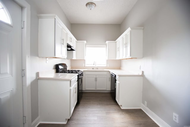 kitchen featuring black gas stove, a sink, a textured ceiling, under cabinet range hood, and dishwashing machine