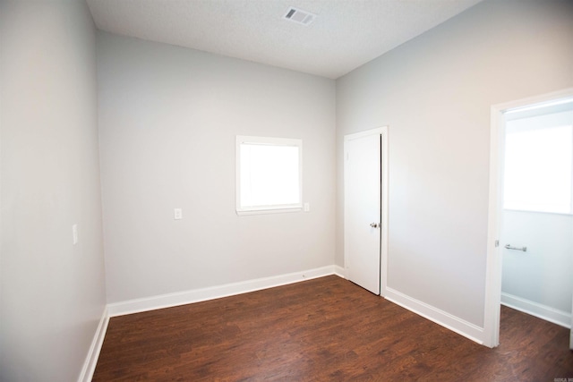 unfurnished room featuring visible vents, dark wood finished floors, and baseboards