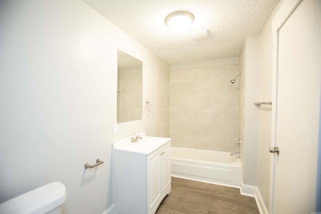 bathroom featuring toilet, washtub / shower combination, vanity, a textured ceiling, and wood finished floors