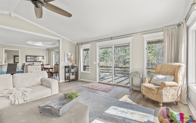 living room with lofted ceiling, ornamental molding, ceiling fan, wood finished floors, and baseboards