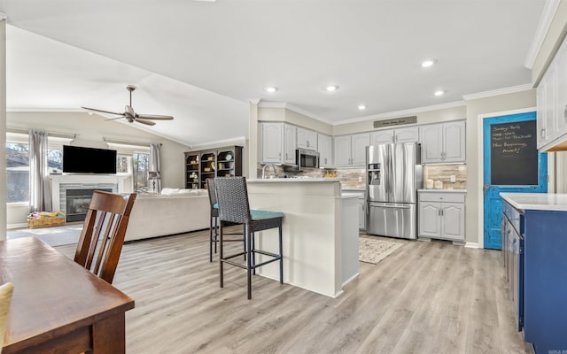 kitchen featuring appliances with stainless steel finishes, a breakfast bar, open floor plan, a peninsula, and vaulted ceiling