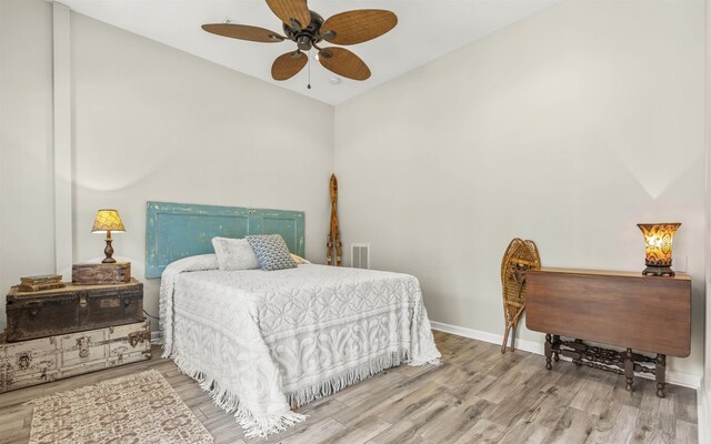 bedroom with wood finished floors, a ceiling fan, visible vents, vaulted ceiling, and baseboards