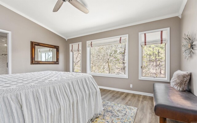 bedroom with wood finished floors, a ceiling fan, baseboards, vaulted ceiling, and ornamental molding