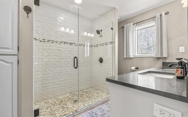 bathroom with double vanity, a stall shower, and a sink