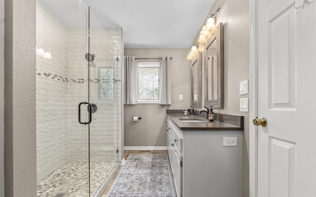 bathroom featuring a stall shower, baseboards, and vanity