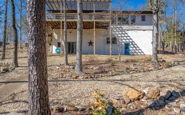 rear view of house featuring a wooden deck and stucco siding