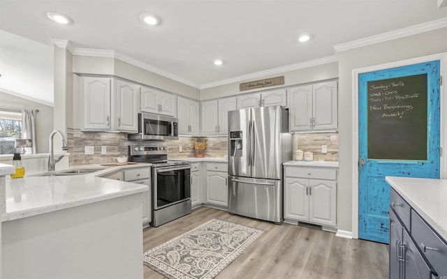 kitchen with stainless steel appliances, tasteful backsplash, light wood-style flooring, ornamental molding, and a sink