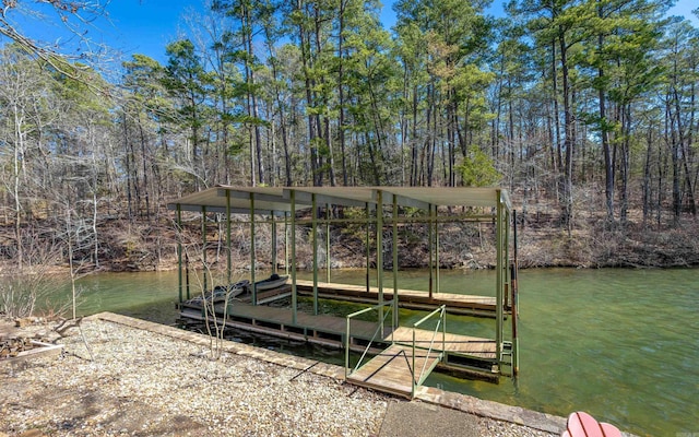 view of dock featuring a water view and a forest view