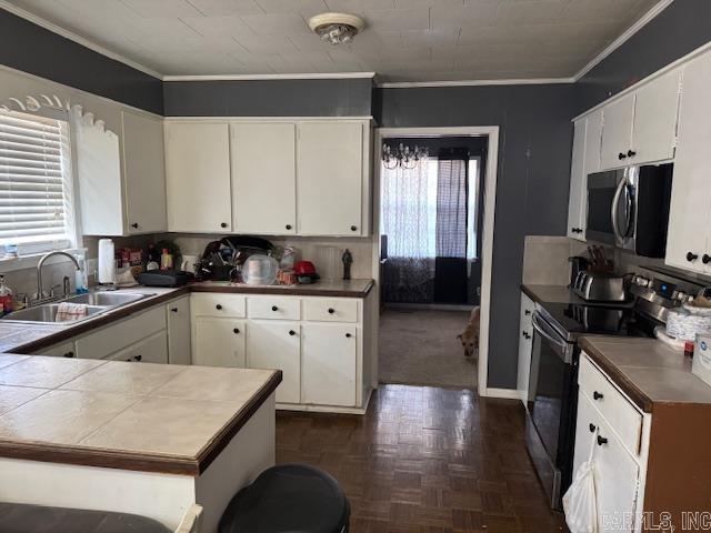 kitchen featuring appliances with stainless steel finishes, a sink, white cabinetry, and crown molding