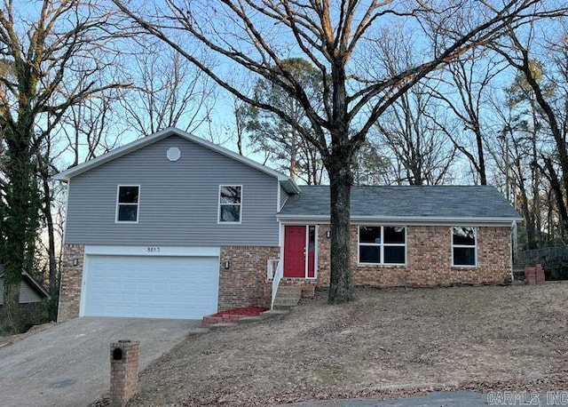 tri-level home with entry steps, driveway, brick siding, and an attached garage