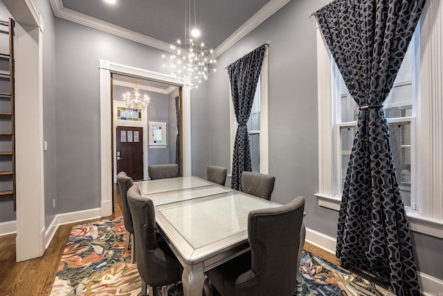 dining space with baseboards, ornamental molding, wood finished floors, and a notable chandelier