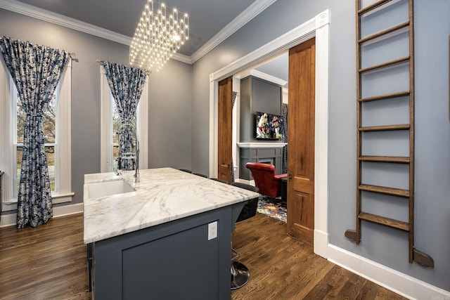 bathroom with a notable chandelier, ornamental molding, a sink, wood finished floors, and baseboards