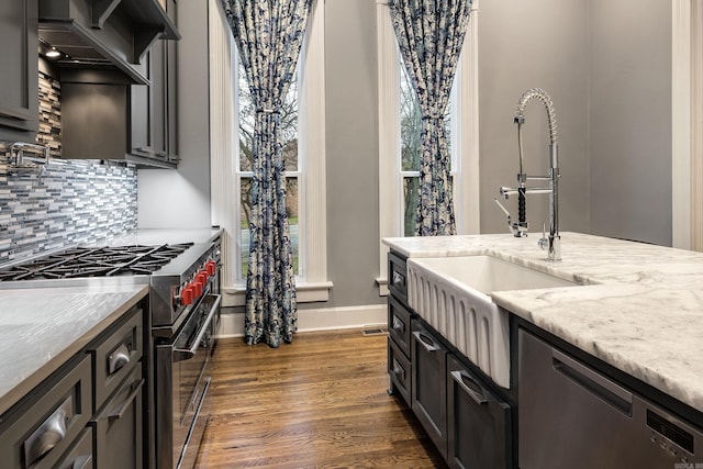 kitchen with dark wood-style floors, stainless steel appliances, tasteful backsplash, custom range hood, and a sink