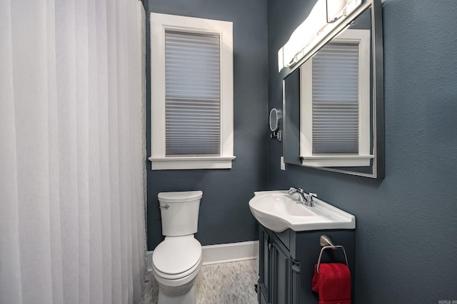 bathroom featuring toilet, wood finished floors, vanity, and baseboards