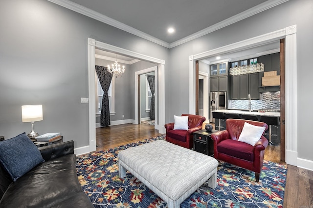 living area with a notable chandelier, baseboards, dark wood finished floors, and crown molding