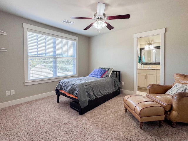 carpeted bedroom with ensuite bathroom, a ceiling fan, visible vents, and baseboards