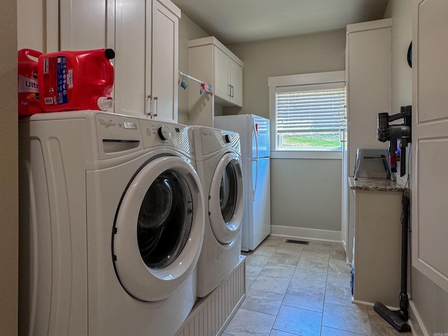 washroom with light tile patterned flooring, visible vents, baseboards, independent washer and dryer, and cabinet space