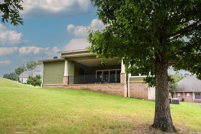 back of property with a yard, central AC unit, and brick siding