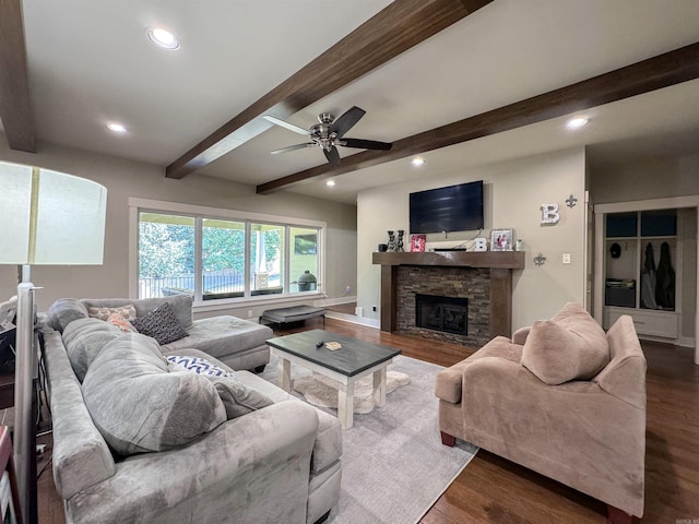 living area featuring dark wood finished floors, beam ceiling, and a stone fireplace