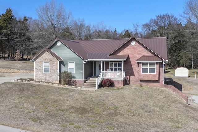 ranch-style house with brick siding, stone siding, metal roof, covered porch, and a front yard