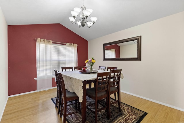 dining area featuring lofted ceiling, baseboards, light wood-style flooring, and a notable chandelier