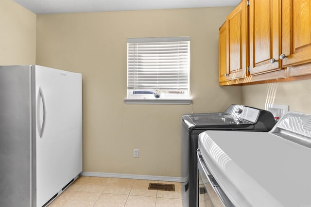 washroom featuring light tile patterned floors, cabinet space, visible vents, washing machine and dryer, and baseboards