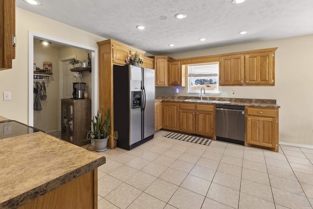 kitchen featuring appliances with stainless steel finishes, brown cabinets, a textured ceiling, a sink, and recessed lighting