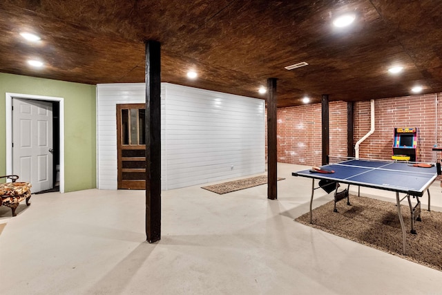 rec room featuring brick wall, finished concrete floors, and recessed lighting