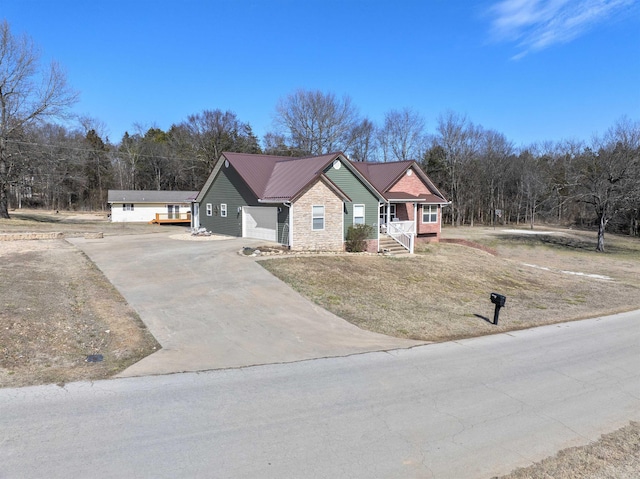 view of front of property with a porch, metal roof, a garage, stone siding, and driveway