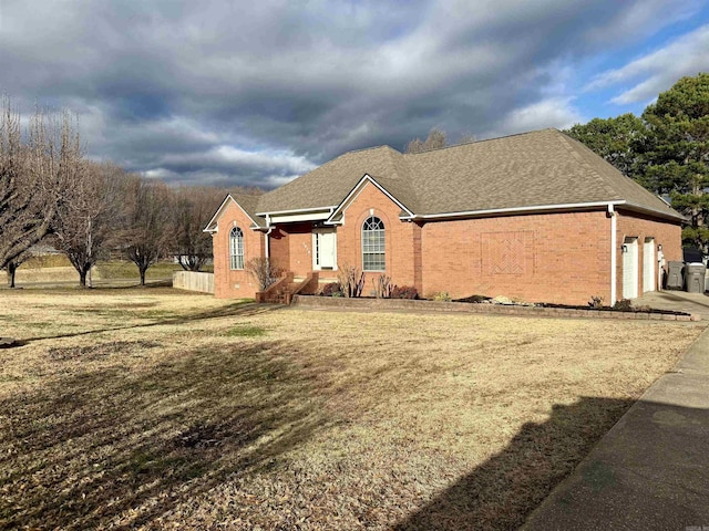 view of front facade featuring a front yard, brick siding, an attached garage, and roof with shingles