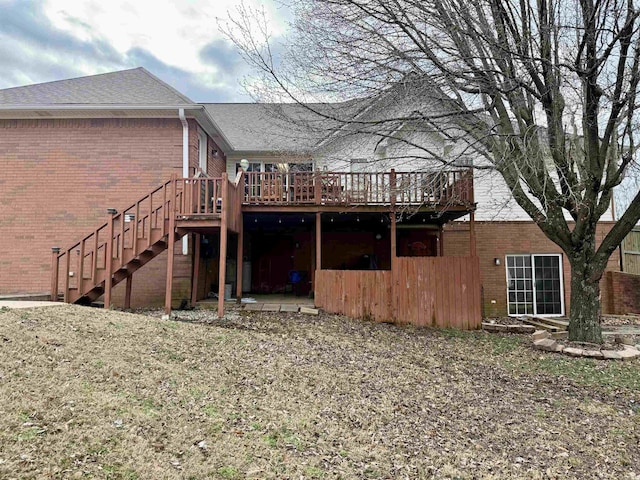 back of house featuring a deck, brick siding, a shingled roof, and stairway