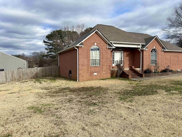 rear view of property featuring crawl space, a shingled roof, fence, and brick siding