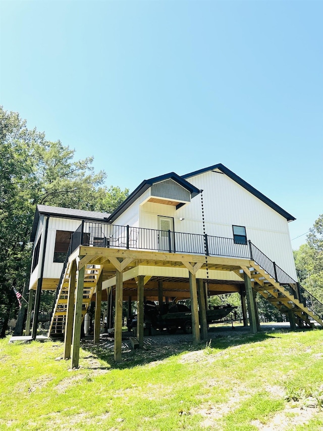 back of property featuring driveway, stairway, a deck, a yard, and a carport