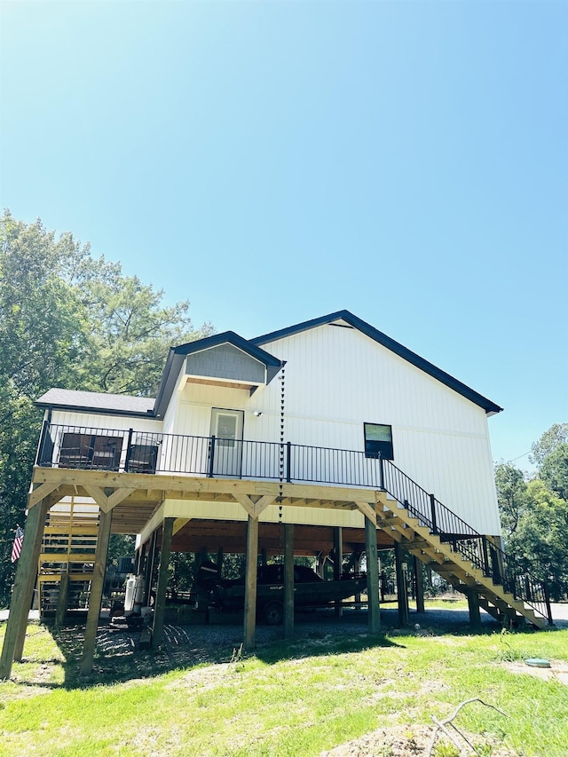 rear view of property featuring a yard, a wooden deck, and stairs