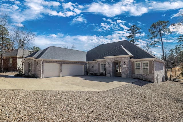 french country inspired facade featuring concrete driveway, brick siding, an attached garage, and roof with shingles