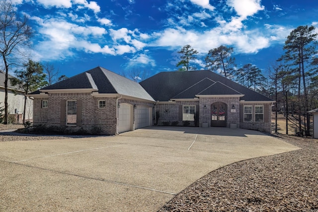 view of front facade with a garage, roof with shingles, concrete driveway, and brick siding